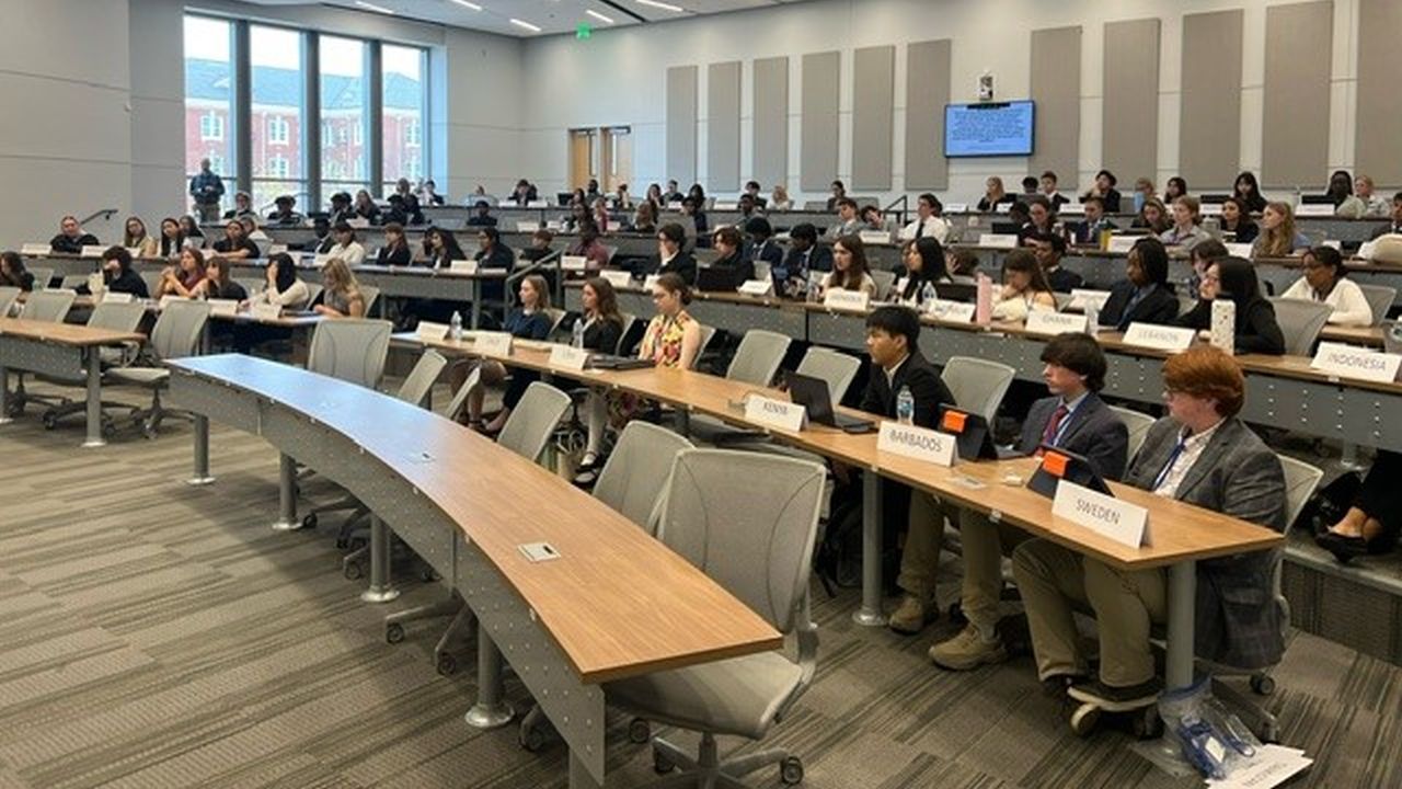 Students seated in a Model UN committee room with country placards